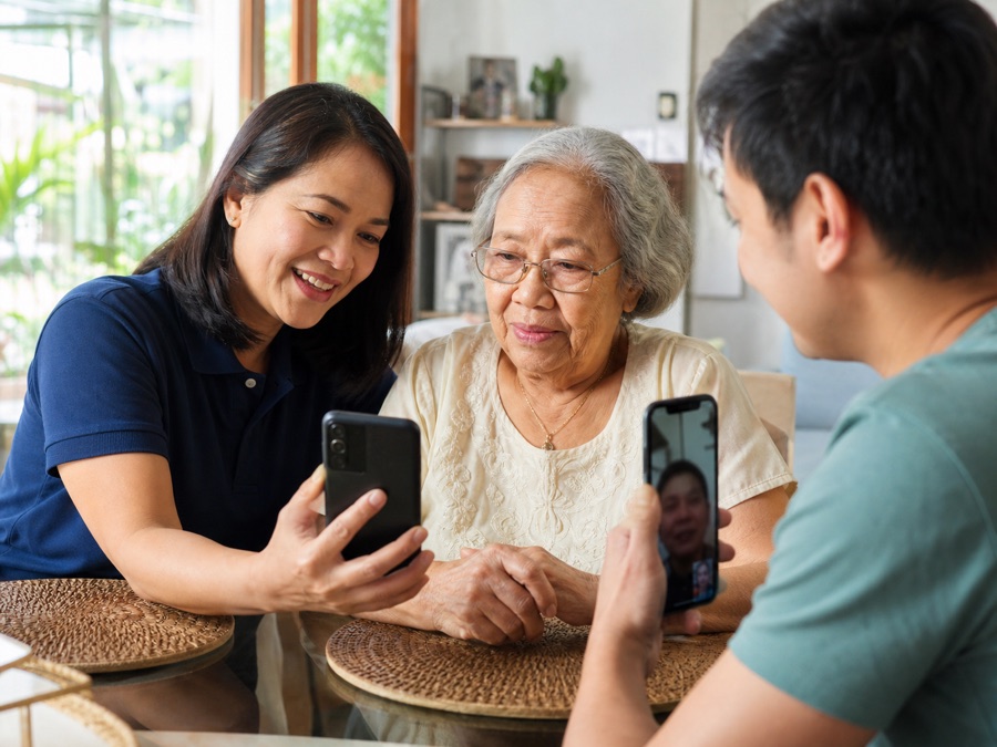 Filipino care coordinator helping a senior connect with family during a welfare visit